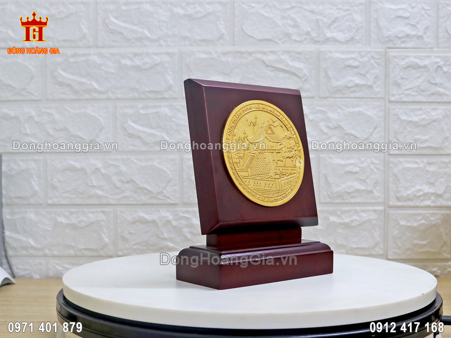 Mặt trống đồng dát vàng 24K đế gỗ được đặt tại bàn làm việc, tủ trưng bày